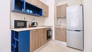 A modern kitchen with wooden cabinets, a stainless steel refrigerator, a microwave, and a kettle. - Cozy 1-bed Apartment (Plovdiv)