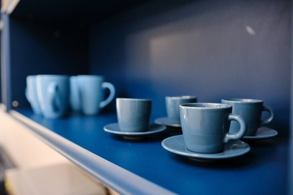 A row of blue cups and saucers on a blue table.