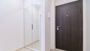 A room with a dark wooden door, a white wall, and a glass partition. - Cozy 1-bed Apartment (Plovdiv)