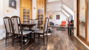 Ein Essbereich mit Holztisch und Stühlen, eine kleine Sitzecke mit Sofa und Sessel sowie eine Treppe, die zu einer oberen Ebene führt.