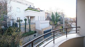 A modern residential building with a balcony, a gated entrance, and a well-maintained garden.