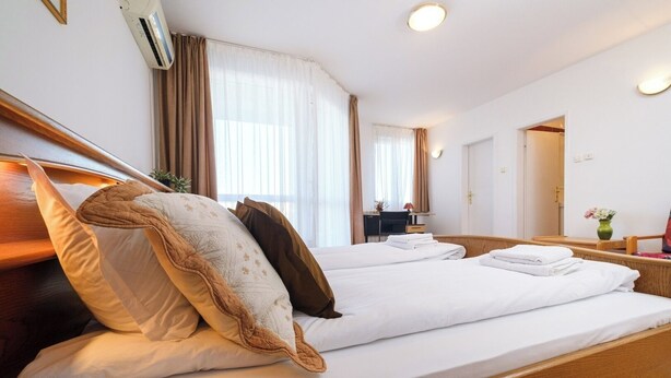 A hotel room with a large bed, a desk, and a chair.