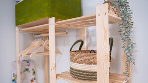 A wooden shelf unit with a woven basket on the middle shelf.