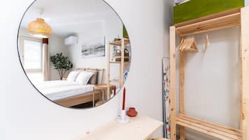 A bedroom with a bed, a bedside table, a mirror, and a hanging light fixture.