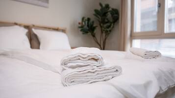 Un lit bien fait, avec des draps blancs et une pile de serviettes pliées posée sur le lit.