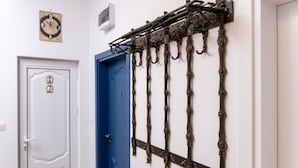 A hallway with a white door, a blue door, and a wall-mounted metal rack with hooks.