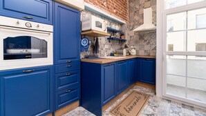 A kitchen with blue cabinets, a white stove, and a brick wall.