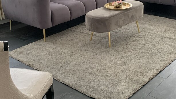 A modern living room with a grey sectional sofa, a round ottoman, and a beige chair. - Accogliente appartamento (Wuppertal)