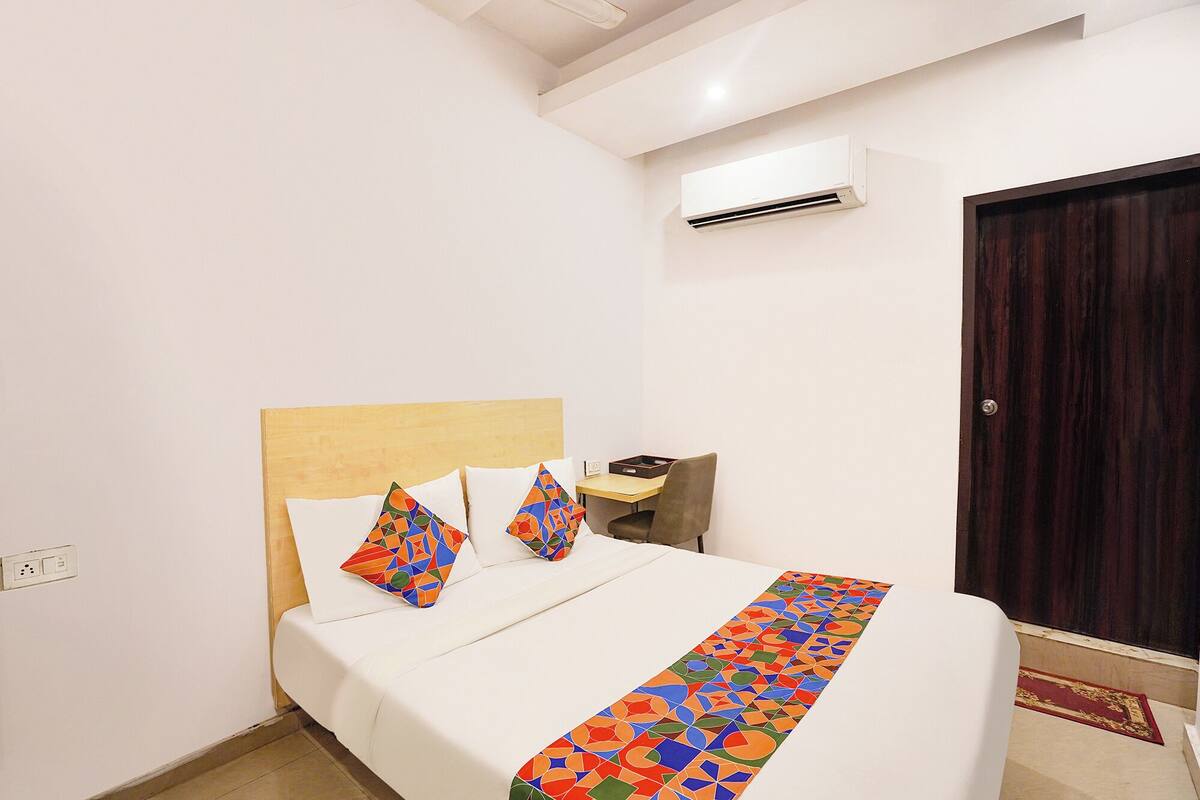 Una habitación de hotel con cama, escritorio, aire acondicionado y puerta.
