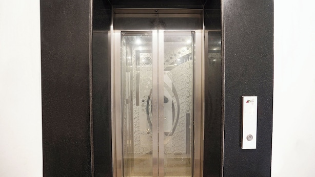 An elevator with a glass door and a metallic handle. - Fabexpress Prime Inn (Prayagraj)