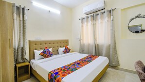 A hotel room with a bed, curtains, an air conditioning unit, and a mirror on the wall. - Fabhotel Rk Suites (Hyderabad)