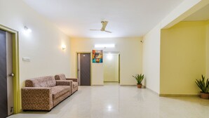 A spacious lobby with a high ceiling, a ceiling fan, a sofa, a potted plant, and a painting on the wall. - Fabhotel Rk Suites (Hyderabad)
