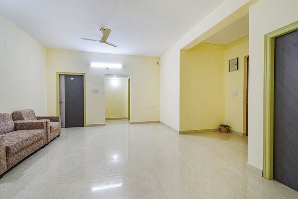A hallway with a ceiling fan, a sofa, and doors leading to other rooms. - Fabhotel Rk Suites (Hyderabad)