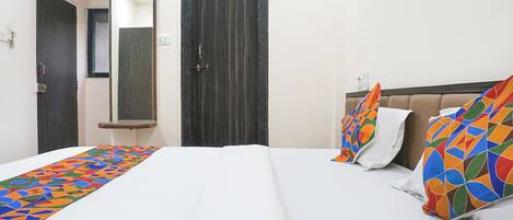 A hotel room with a bed, a mirror, and a door.