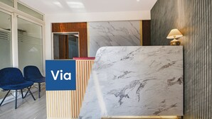 A reception desk with a marble top, two blue chairs, and a 'Via' sign. - Fabhotel Ar Suites (Gurugram)