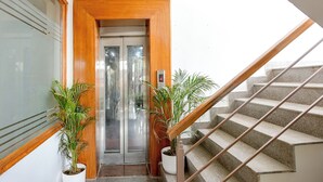 An elevator with a wooden frame, a digital display, and potted plants beside it. - Fabhotel Ar Suites (Gurugram)