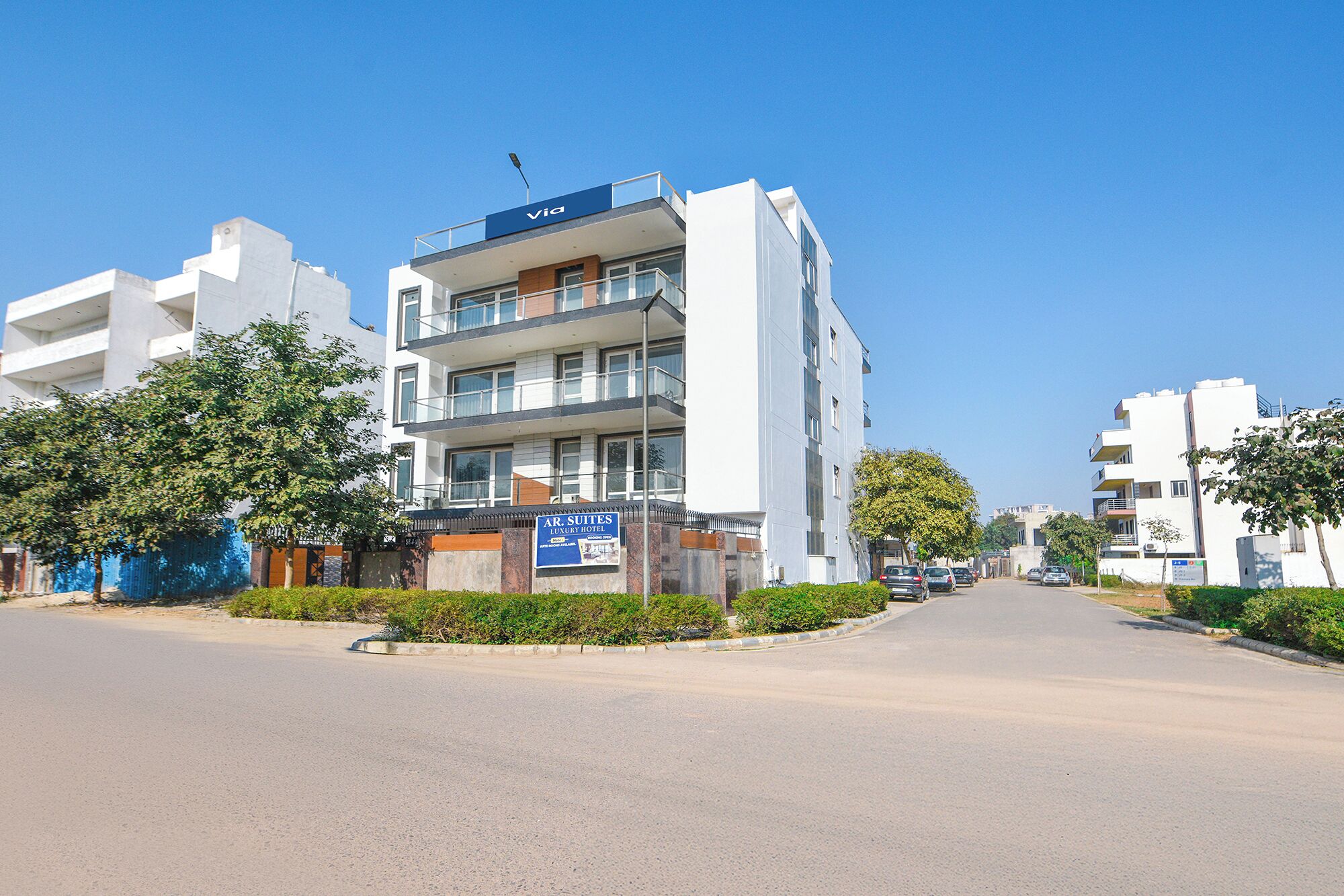A modern multi-story building with a sign for 'AR SUITES LUXURY HOTEL'.