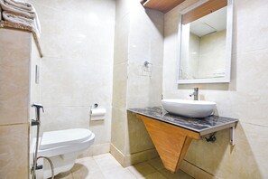 A bathroom with a white toilet, a sink with a marble countertop, and a mirror above the sink.