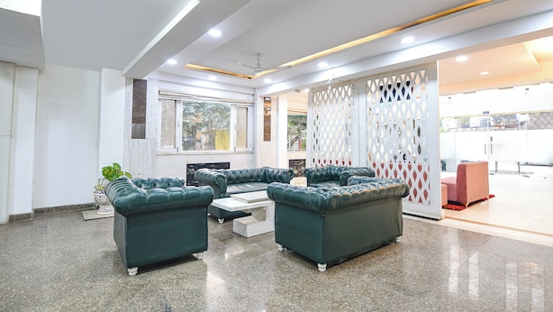 Een moderne lobby met groene leren banken, een witte salontafel en een decoratieve witte rasterwand.