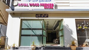 Der Eingang zu Royal Wood Premier Rooms mit einem Schild in Englisch und einer weiteren Sprache, einer nach oben führenden Treppe und Blumentöpfen am Eingang.