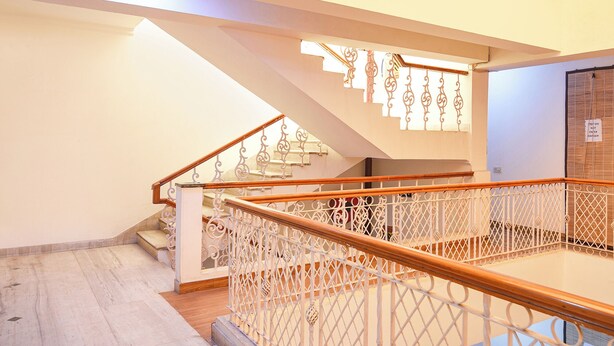 Una escalera con barandillas blancas ornamentales y pasamanos de madera, que conduce a un piso superior.