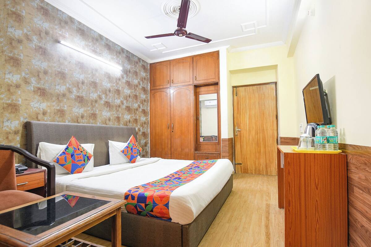 A hotel room with a bed, a desk, a chair, a wardrobe, and a mirror.