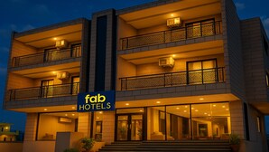 Et hotel med flere etager, moderne facade, altaner og et skilt med teksten 'fab hotels'.