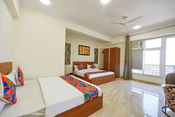 A hotel room with two beds, a ceiling fan, a large window with a view, and a wardrobe.