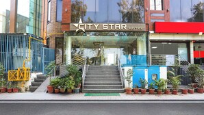 Das Stadtbild des City Star Hotels mit Glastür, Außentreppe und Blumentöpfen.