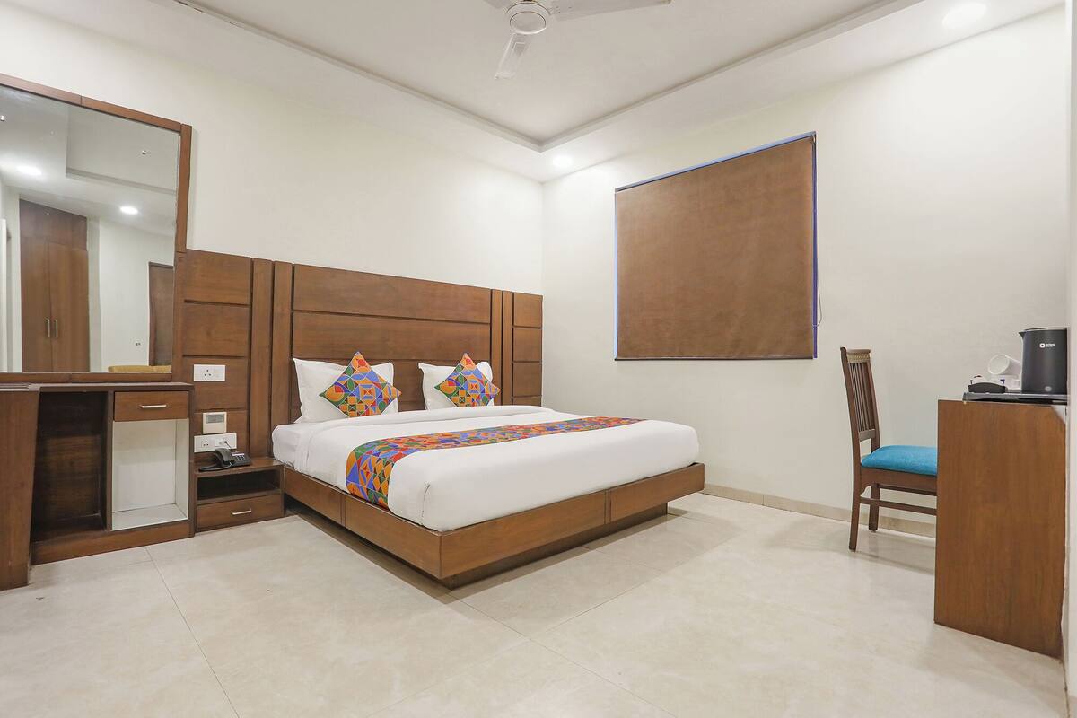 A neatly arranged hotel room with a wooden bed, a desk, and a chair.