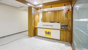 A reception desk with a wooden finish and a sign reading "RECEPTION" and "fab hotels". - Fabhotel Raj Villa (Gandhinagar)