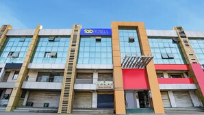 A multi-story building with a prominent 'fabHOTELS' sign, a visible 'KRISHNA ENTERPRISE' sign, and a ladder leading to an upper floor. - Fabhotel Raj Villa (Gandhinagar)