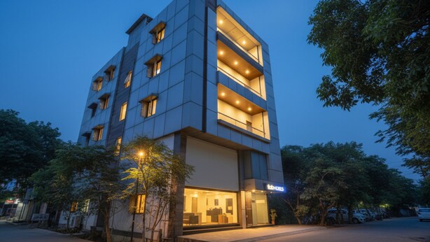 A modern hotel with a glass facade, multiple balconies, and a well-lit entrance. - Fabhotel Just Inn (New Delhi)