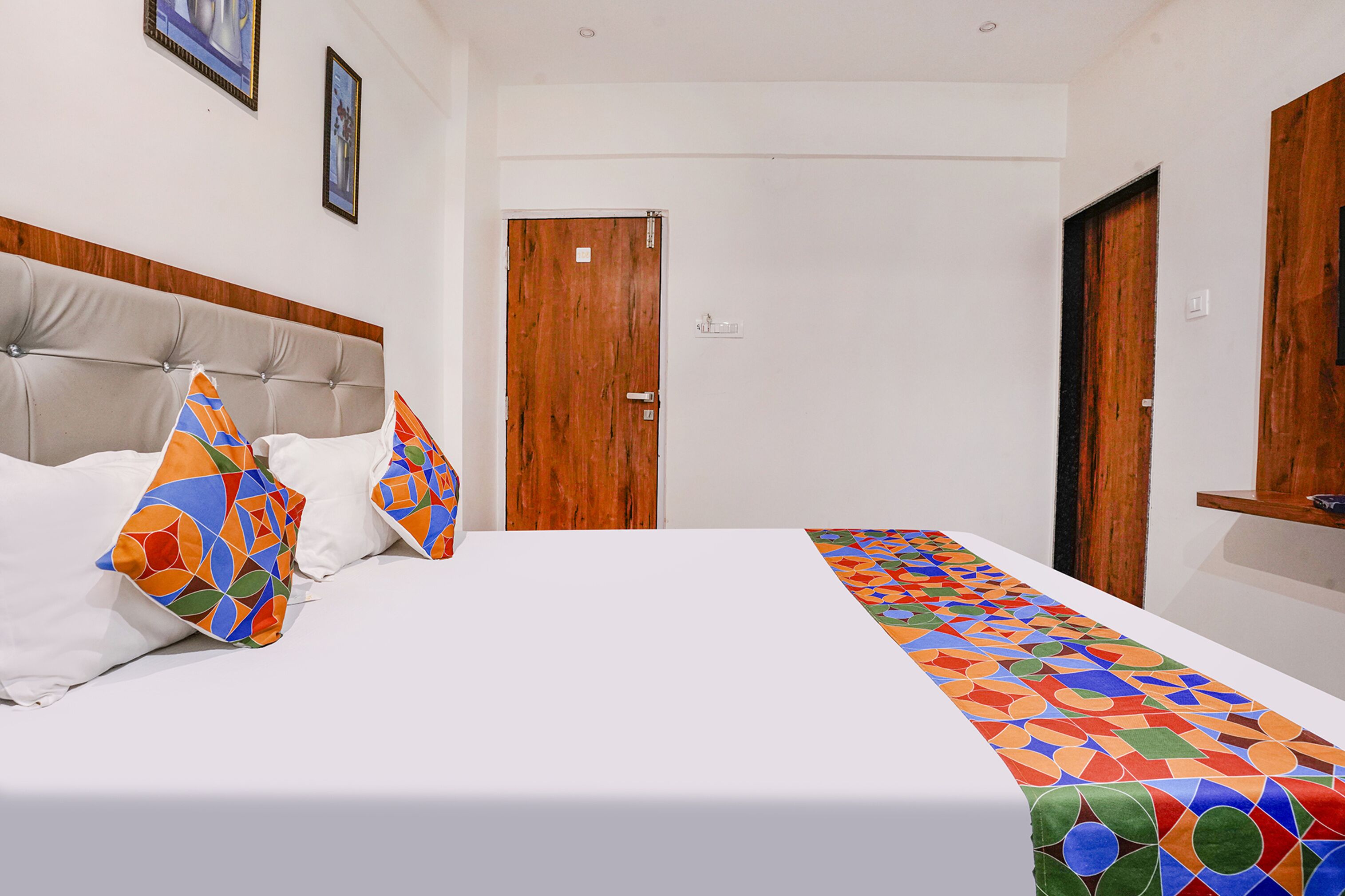 Una habitación de hotel con una cama, una puerta de madera y una pared blanca.