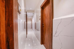 A hallway with wooden doors and marble walls. - FabHotel Utsav Residency (Panvel)