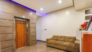 Um hall de entrada com parede de pedra, elevador, sofá e balcão de recepção.