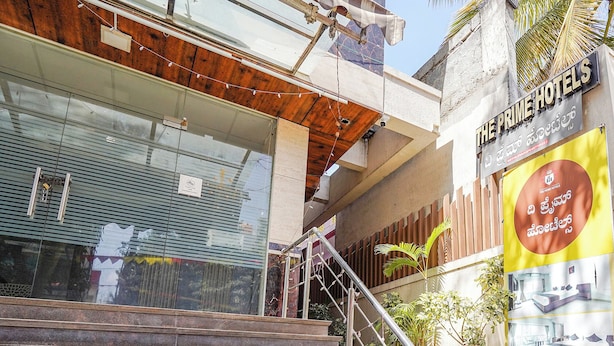 Entrada de hotel com escadaria que leva a uma porta de madeira, corrimão de metal e um grande letreiro com texto.