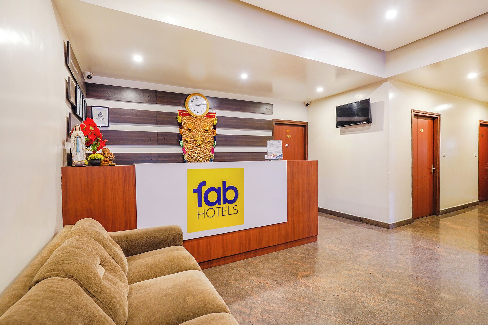 A hotel reception desk with a 'fab hotels' sign, a clock, and a security camera.