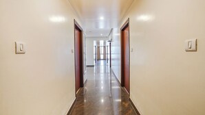 Um corredor com piso encerado, paredes claras e portas em ambos os lados.