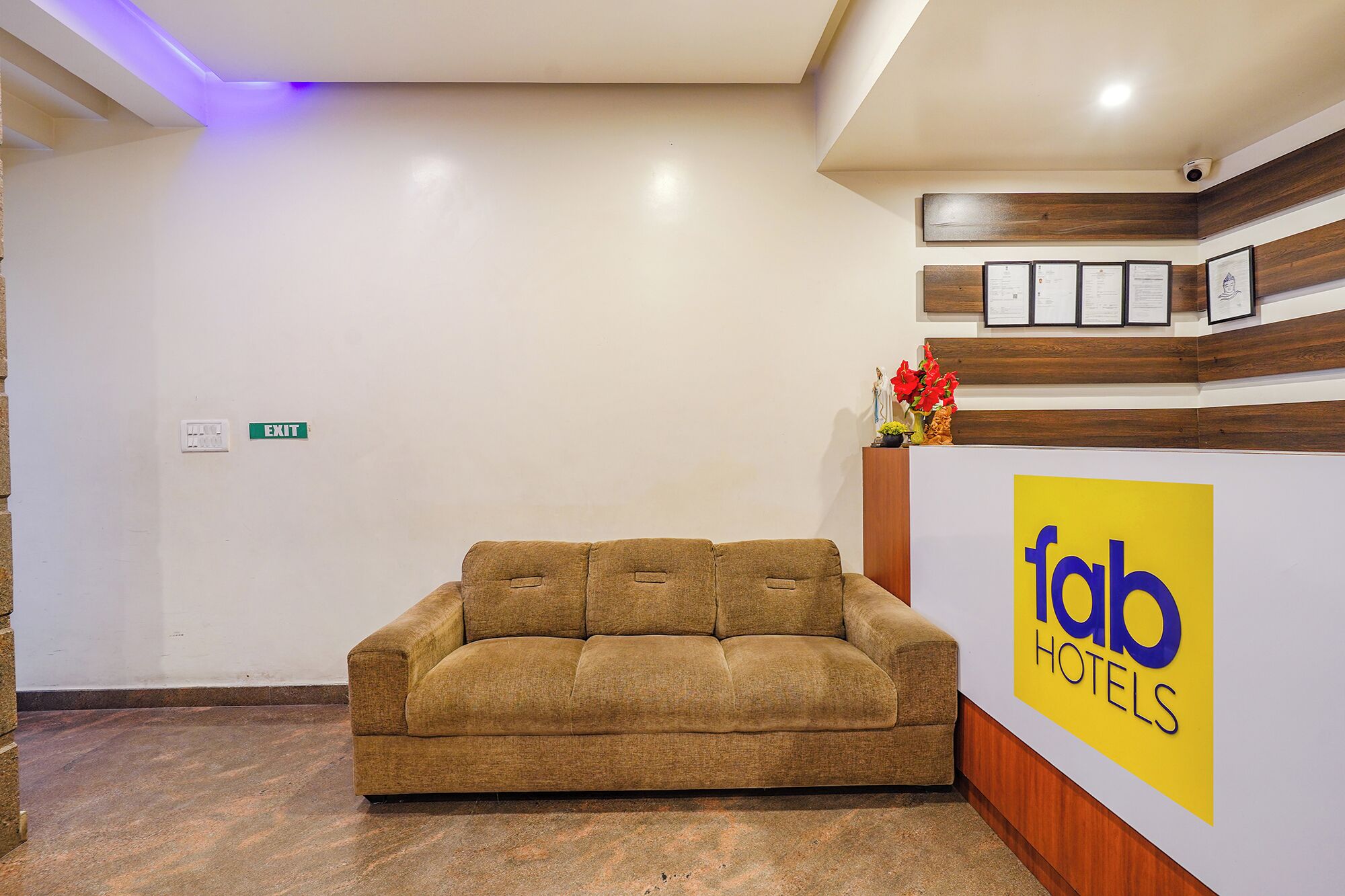 A reception area with a sofa, a wooden reception desk, and a sign for 'fab hotels'.
