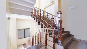 A multi-level interior with a wooden staircase, a fire exit sign, and a window. - Fabhotel Ink (Coimbatore)