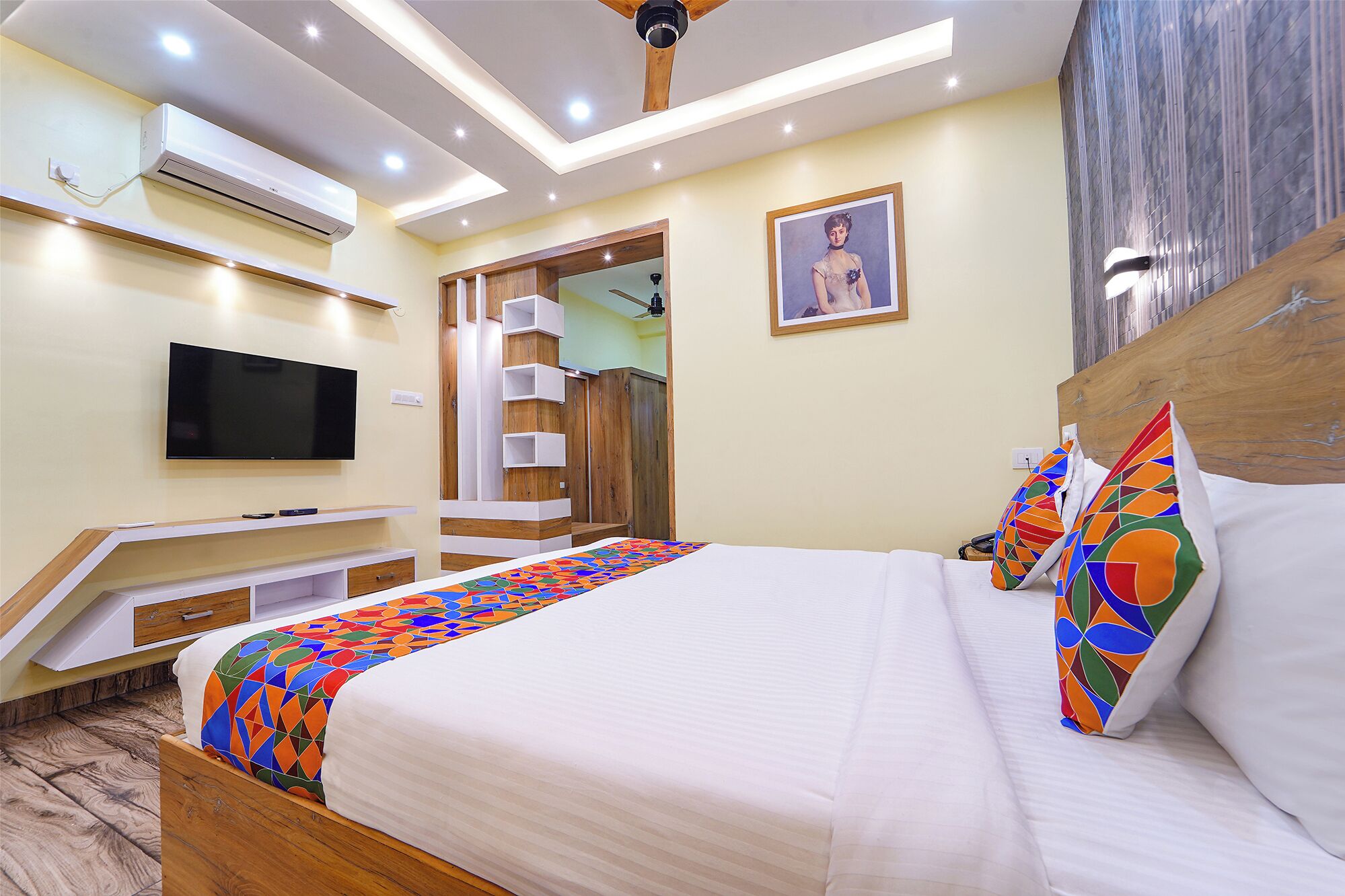 A modern hotel room with a bed, a flat-screen TV, a ceiling fan, and a built-in wardrobe.