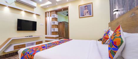A modern hotel room with a bed, a flat-screen TV, a ceiling fan, and a built-in wardrobe.