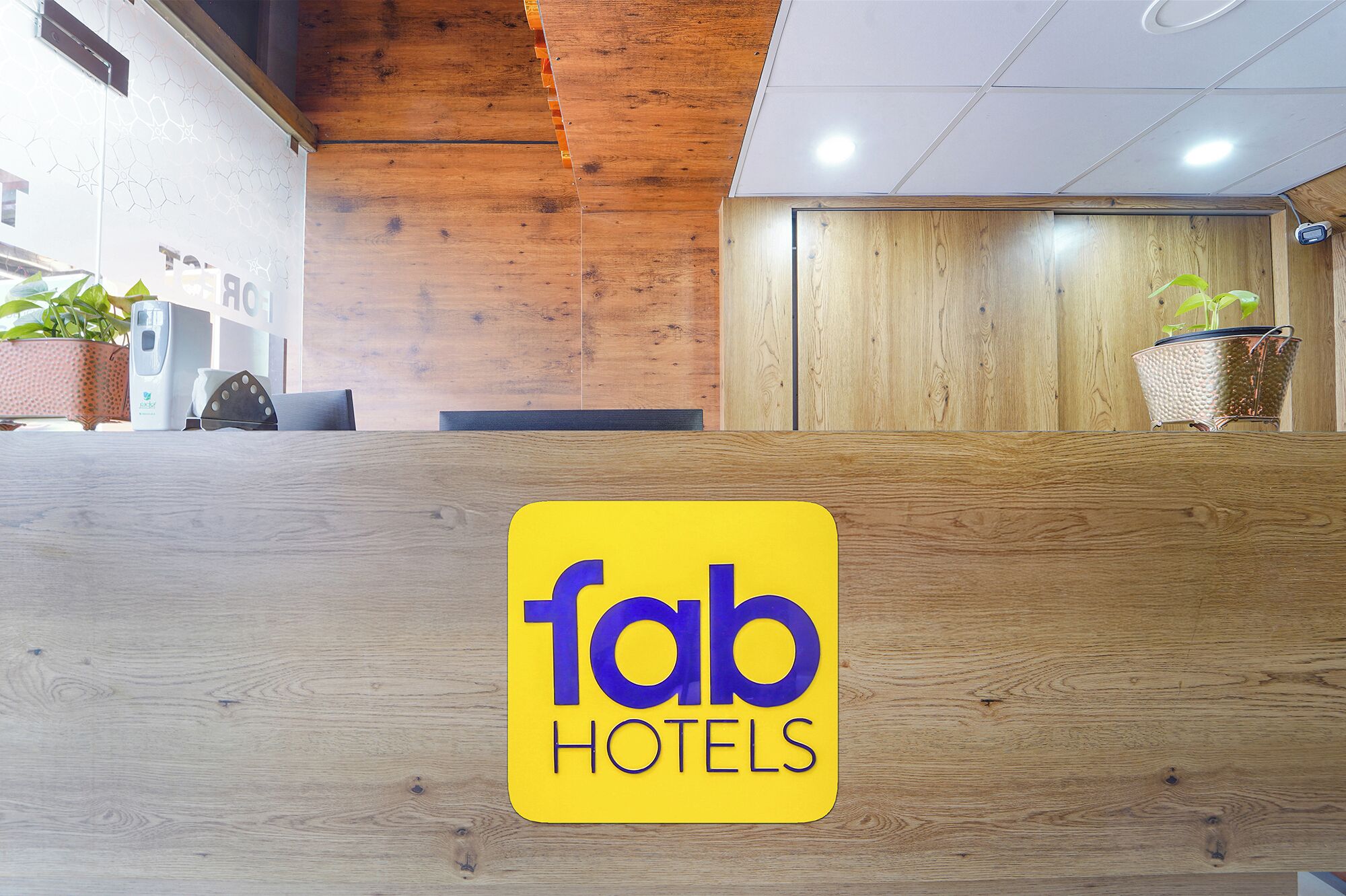 A reception desk with a 'Tab Hotels' sign, wooden paneling, and a potted plant.