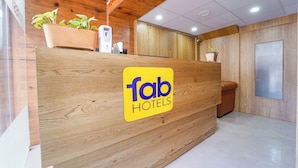A reception desk with a wooden finish, a 'fab hotels' sign, and potted plants. - Fabhotel Ink (Coimbatore)