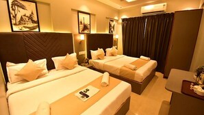 A hotel room with two beds, a desk, and artwork on the walls.
