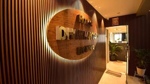 A hotel reception area with a wooden wall and a circular sign displaying the hotel's name.