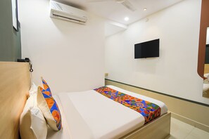 A hotel room with a bed, a flat-screen TV mounted on the wall, and an air conditioning unit above the bed. - Fabhotel The Botanica (Hyderabad)
