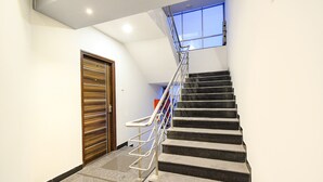 Eine moderne Treppe mit Metallgeländern, einer Holztür und einem Fenster am Obergeschoss.
