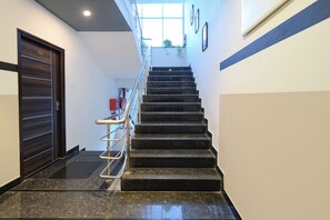 A staircase with a handrail, a closed door, and a window at the top. - Fabhotel The Botanica (Hyderabad)